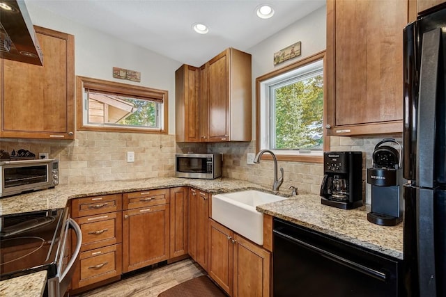 kitchen featuring a toaster, brown cabinets, black appliances, range hood, and a sink