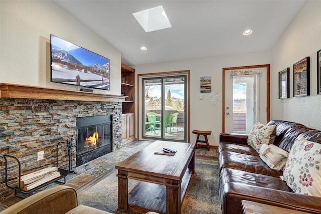 living room with a skylight, built in features, a fireplace, and plenty of natural light