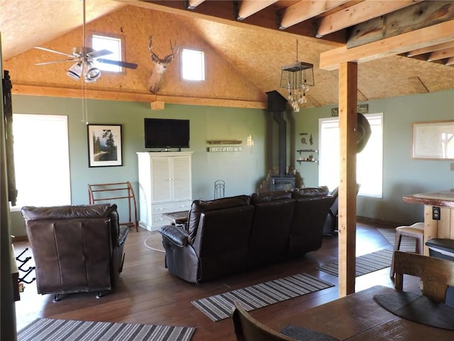 living area with ceiling fan, plenty of natural light, a wood stove, and dark wood finished floors