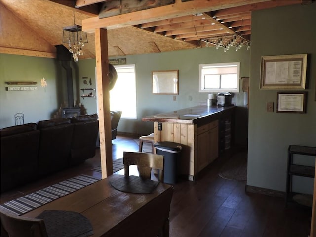 kitchen with lofted ceiling with beams, a chandelier, a wood stove, baseboards, and dark wood-type flooring