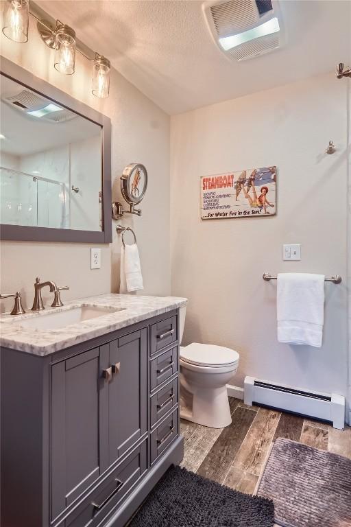 1437 Morgan Ct Unit 1437, Steamboat Springs, CO 80487 - bathroom featuring a baseboard heating unit, wood finished floors, vanity, and a shower stall