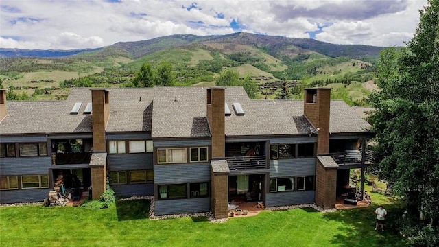101 Blue Grouse Ln Unit D, Silverthorne, CO 80498 - rear view of property featuring a chimney, a mountain view, a lawn, and a balcony