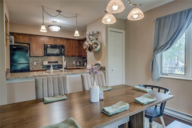 101 Blue Grouse Ln Unit D, Silverthorne, CO 80498 - kitchen featuring black appliances, backsplash, light stone counters, decorative light fixtures, and a peninsula