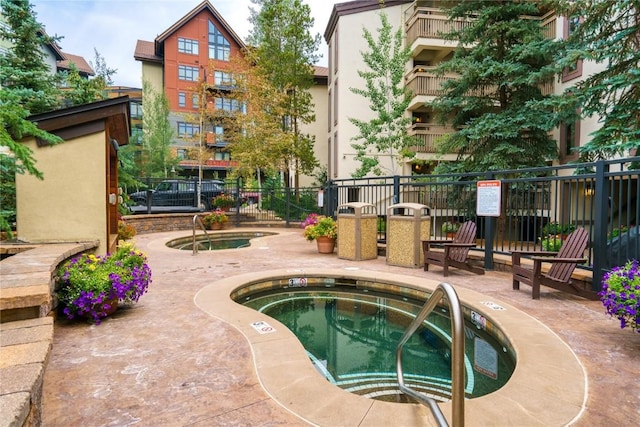 view of swimming pool with a patio area, a hot tub, and fence