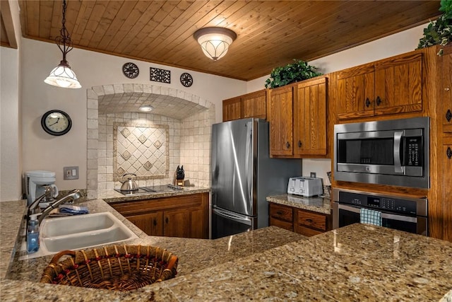 kitchen with a sink, brown cabinets, light stone countertops, decorative light fixtures, and appliances with stainless steel finishes