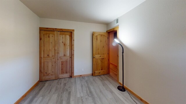 unfurnished bedroom with baseboards, light wood-style flooring, and visible vents