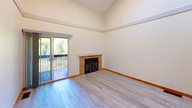 unfurnished living room featuring high vaulted ceiling, baseboards, wood finished floors, and visible vents