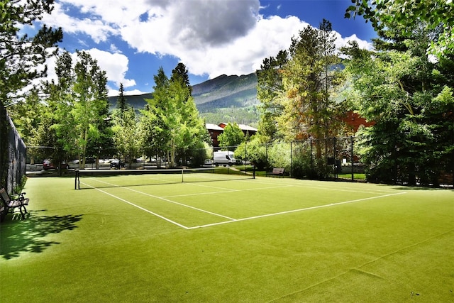 view of tennis court featuring fence and a mountain view