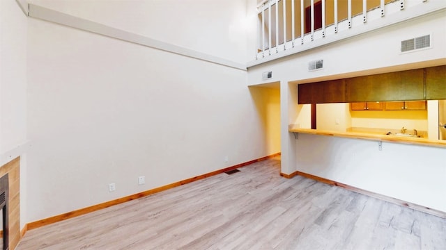 unfurnished living room featuring wet bar, wood finished floors, visible vents, and baseboards