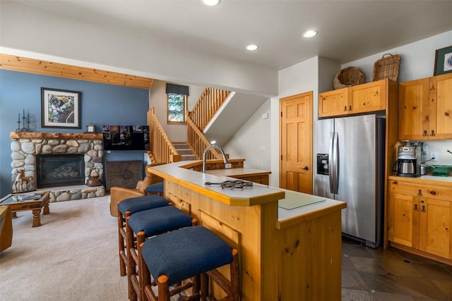 2838 Kitzbuhel Court ., Steamboat Springs, CO 80487 - kitchen with recessed lighting, stainless steel fridge with ice dispenser, light countertops, a stone fireplace, and a breakfast bar