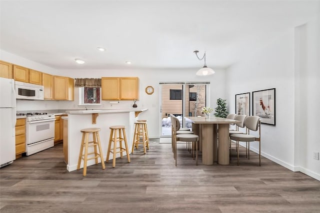 3462 Sunburst Ct Unit 36, Steamboat Springs, CO 80487 - kitchen featuring white appliances, light brown cabinetry, a breakfast bar, light countertops, and recessed lighting