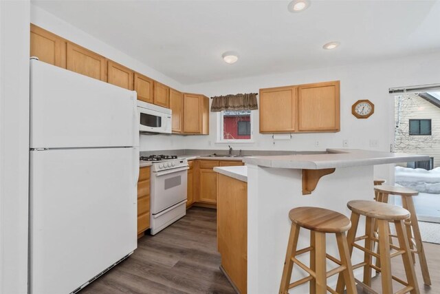 3462 Sunburst Ct Unit 36, Steamboat Springs, CO 80487 - kitchen with white appliances, a sink, a breakfast bar, dark wood-style flooring, and light countertops