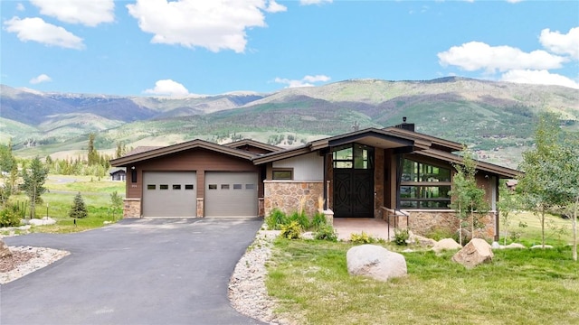304 Raven Golf Ln, Silverthorne, CO 80498 - view of front of property featuring stone siding, a mountain view, an attached garage, and asphalt driveway