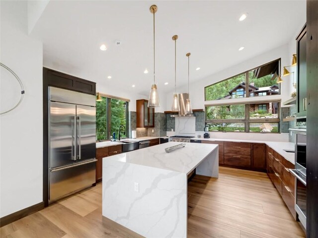 304 Raven Golf Ln, Silverthorne, CO 80498 - kitchen featuring stainless steel appliances, a center island, light wood-style flooring, decorative backsplash, and decorative light fixtures