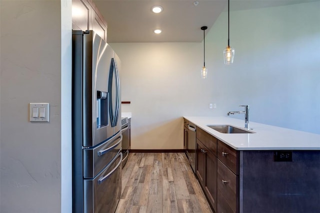 320 Fox Springs Cir Unit 302, Steamboat Springs, CO 80487 - kitchen with appliances with stainless steel finishes, a sink, a peninsula, light wood-style floors, and dark brown cabinetry