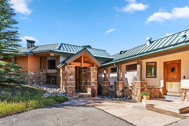 731 Lakeview Cir, Silverthorne, CO 80498 - view of front of house featuring a standing seam roof, stone siding, metal roof, a chimney, and a porch
