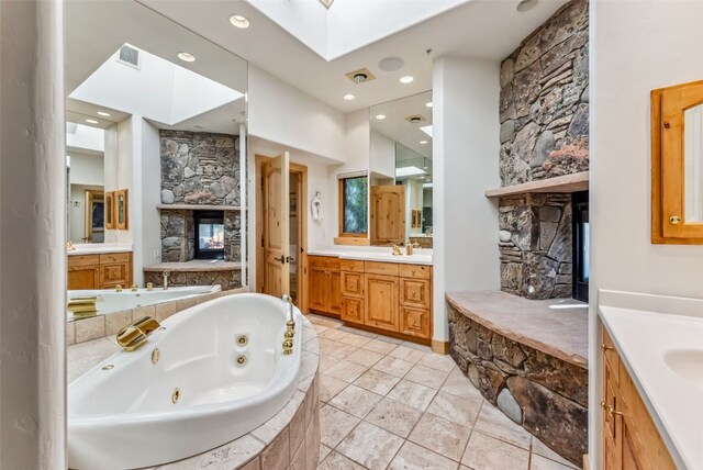 731 Lakeview Cir, Silverthorne, CO 80498 - full bathroom featuring a multi sided fireplace, two vanities, a tub with jets, a skylight, and recessed lighting