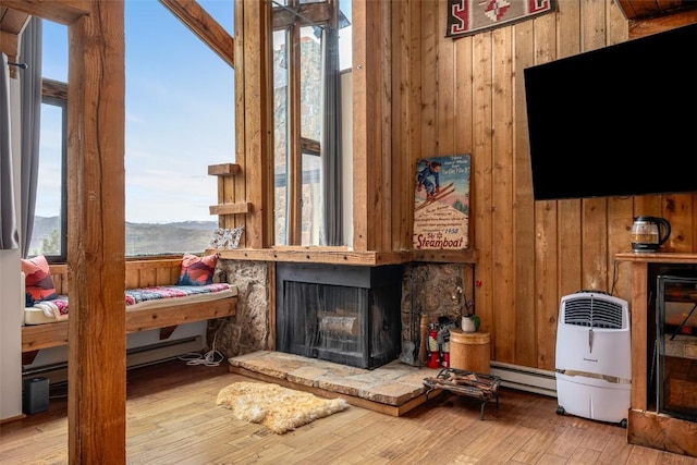 31500 Runaway Pl Unit 405, Steamboat Springs, CO 80487 - living area featuring a baseboard radiator, wooden walls, wood finished floors, and a fireplace with raised hearth