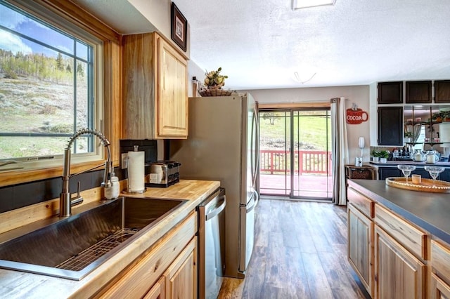 420 County Rd 130, Kremmling, CO 80459 - kitchen with a sink, appliances with stainless steel finishes, wood finished floors, a textured ceiling, and light brown cabinetry