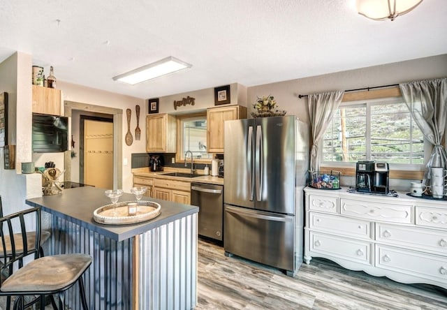 420 County Rd 130, Kremmling, CO 80459 - kitchen featuring stainless steel appliances, a sink, light brown cabinetry, light wood-style flooring, and a kitchen breakfast bar