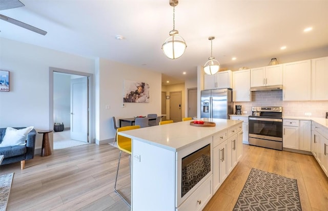 75 W 4th St Unit 206, Silverthorne, CO 80497 - kitchen featuring stainless steel appliances, under cabinet range hood, light wood-type flooring, light countertops, and a kitchen island