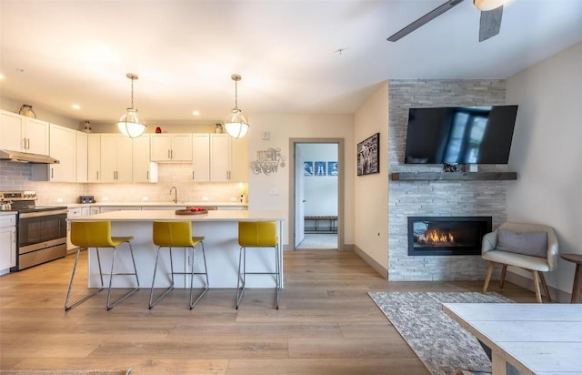 75 W 4th St Unit 206, Silverthorne, CO 80497 - kitchen with stainless steel range with electric cooktop, a sink, under cabinet range hood, a center island, and decorative backsplash