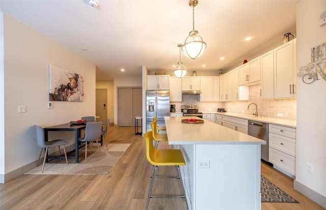 75 W 4th St Unit 206, Silverthorne, CO 80497 - kitchen with appliances with stainless steel finishes, a center island, light wood-type flooring, tasteful backsplash, and light countertops