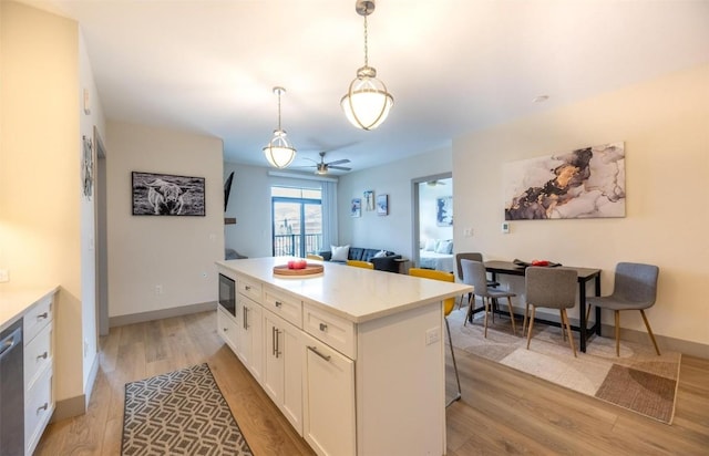 75 W 4th St Unit 206, Silverthorne, CO 80497 - kitchen with black microwave, light wood finished floors, white cabinetry, a center island, and pendant lighting