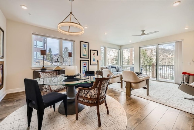 dining area with wood finished floors, a wealth of natural light, a ceiling fan, and baseboards