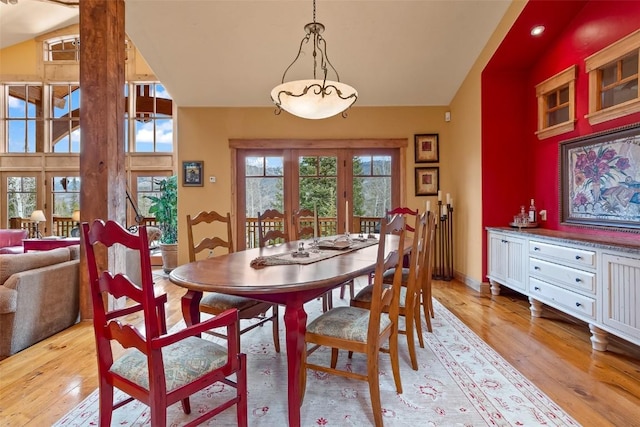 dining space with baseboards, vaulted ceiling, and light wood finished floors