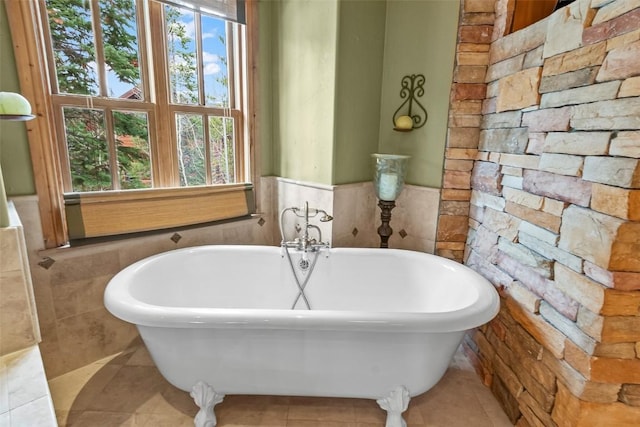 full bath featuring wainscoting, a soaking tub, and tile patterned flooring