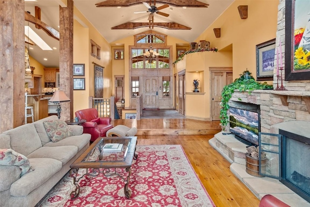 living room featuring a notable chandelier, a fireplace, wood-type flooring, high vaulted ceiling, and beamed ceiling