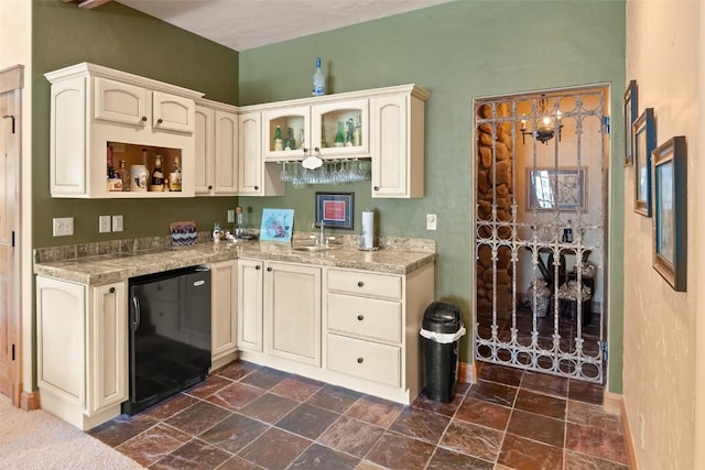 kitchen featuring baseboards, stone finish flooring, cream cabinets, and refrigerator