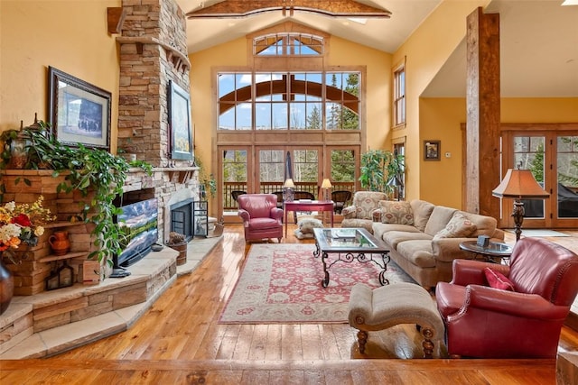 living area with high vaulted ceiling, a fireplace, and hardwood / wood-style flooring