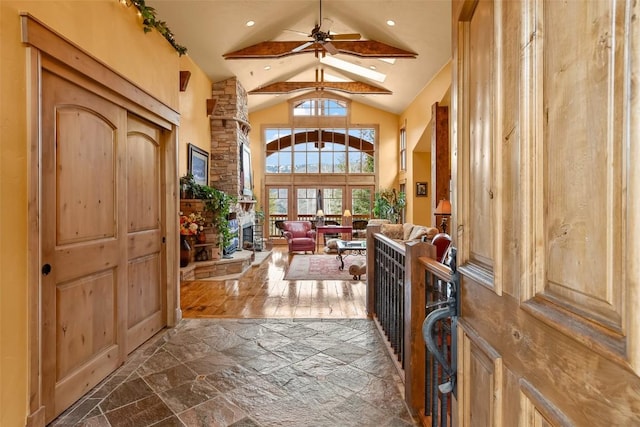 foyer entrance featuring a ceiling fan, stone finish flooring, and high vaulted ceiling
