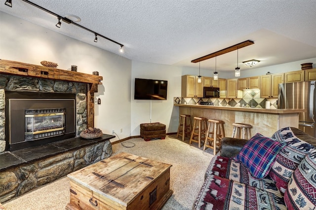 840 Four Oclock Rd Unit A1D, Breckenridge, CO 80424 - carpeted living area featuring a textured ceiling, a stone fireplace, and track lighting