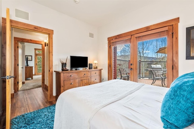 bedroom with visible vents, baseboards, wood finished floors, and access to exterior