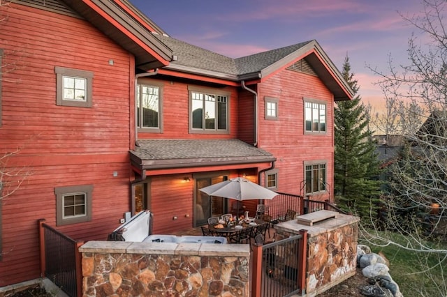 back of property with a shingled roof and a gate