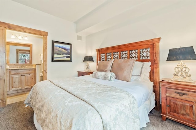 bedroom with a sink, connected bathroom, and light colored carpet