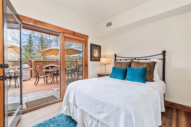 bedroom featuring access to outside, visible vents, multiple windows, and wood finished floors