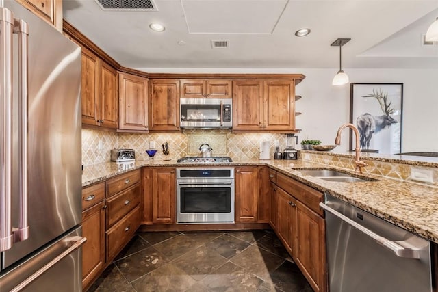 kitchen with brown cabinets, stainless steel appliances, visible vents, and a sink