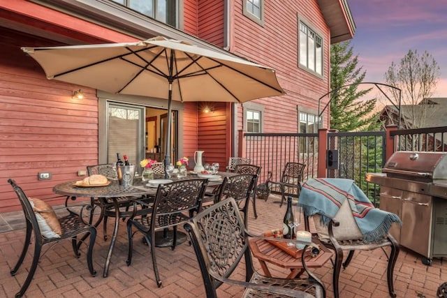 patio terrace at dusk with outdoor dining area and a grill