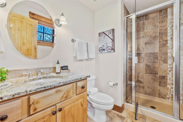 bathroom featuring toilet, baseboards, a shower stall, and vanity