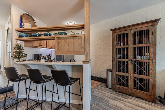 1920 Ski Time Square Dr Unit 315, Steamboat Springs, CO 80487 - kitchen with open shelves, a breakfast bar, light wood-type flooring, light countertops, and a peninsula