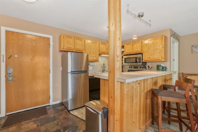 kitchen with appliances with stainless steel finishes, light countertops, light brown cabinetry, and a sink