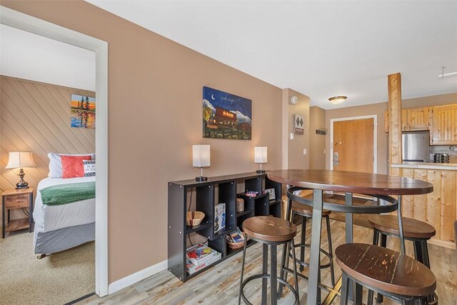 bar with freestanding refrigerator, light wood-style flooring, and baseboards