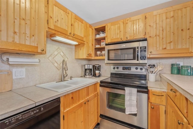 kitchen with appliances with stainless steel finishes, tasteful backsplash, a sink, light countertops, and light brown cabinetry