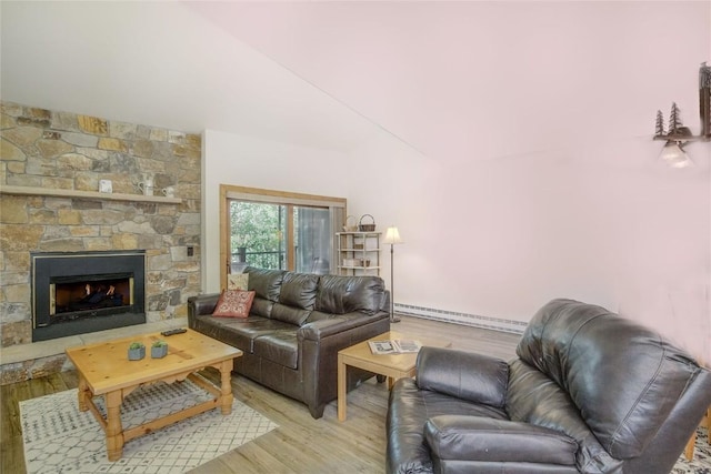 living area featuring a baseboard radiator, light wood-type flooring, lofted ceiling, and a stone fireplace