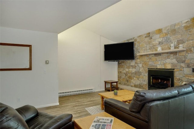 living area featuring a baseboard radiator, vaulted ceiling, a stone fireplace, wood finished floors, and baseboards