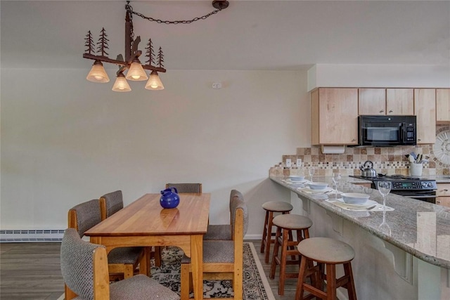 dining space with wood finished floors and a baseboard radiator